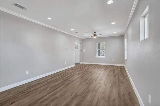 a view of an empty room with a window and wooden floor