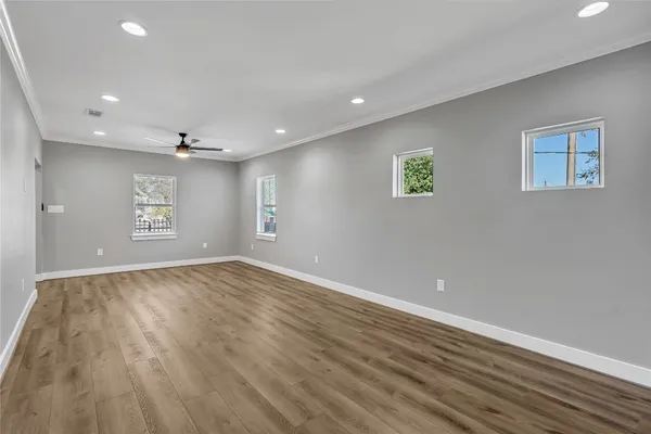 an empty room with wooden floor closet and windows
