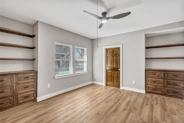 a view of an empty room with a window and wooden floor