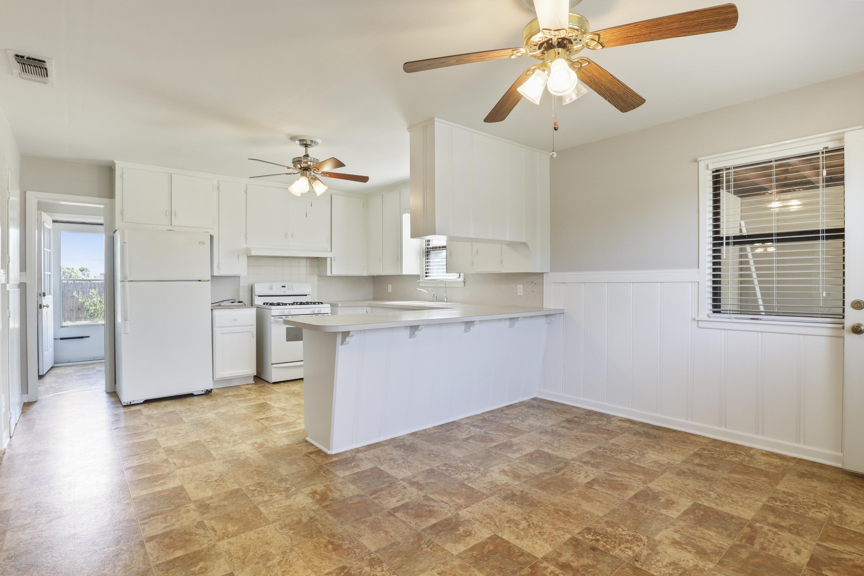 511 6th Street Wolfforth, TX 79382 - Photo 4 of 26 a kitchen with kitchen island cabinets a sink a stove and a refrigerator