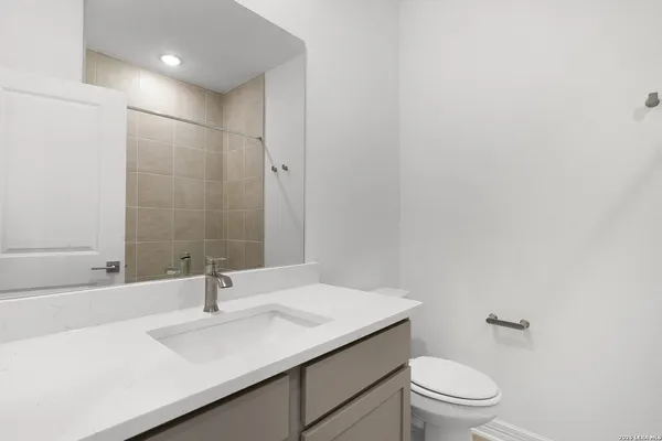 a bathroom with a granite countertop sink a toilet and a mirror