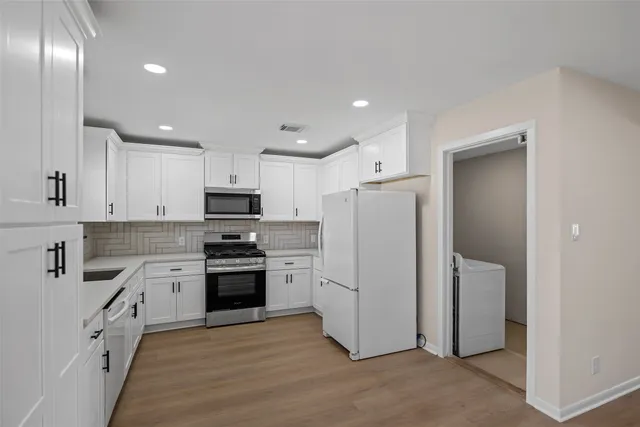a kitchen with granite countertop white cabinets and stainless steel appliances