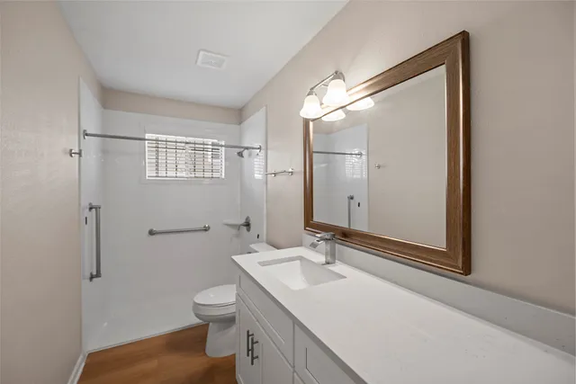 a bathroom with a toilet a sink a mirror and a shower