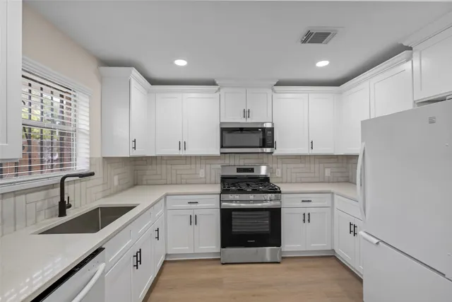 a kitchen with cabinets stainless steel appliances a sink and wooden floor