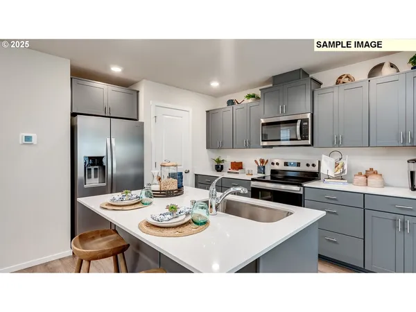 a kitchen with kitchen island a white counter top space a sink appliances and cabinets