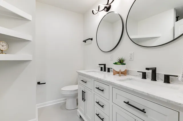 a bathroom with a granite countertop toilet a sink and a mirror