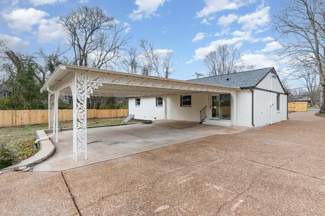 a view of a white house with large tree and wooden fence