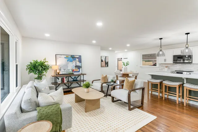 a living room with furniture kitchen view and a wooden floor