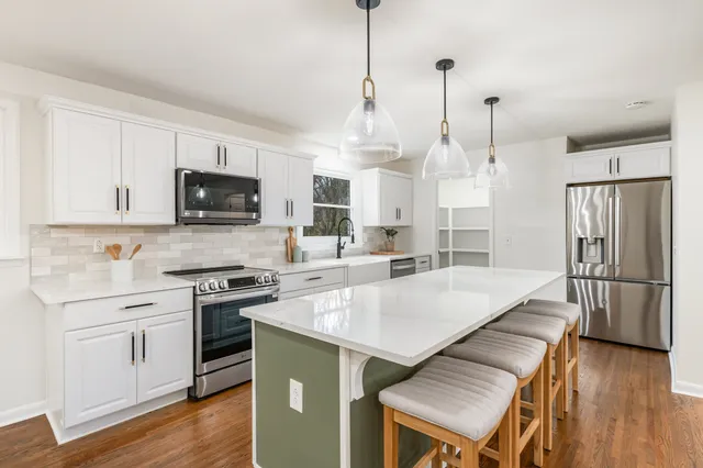 a kitchen with kitchen island a sink stainless steel appliances and wooden floor