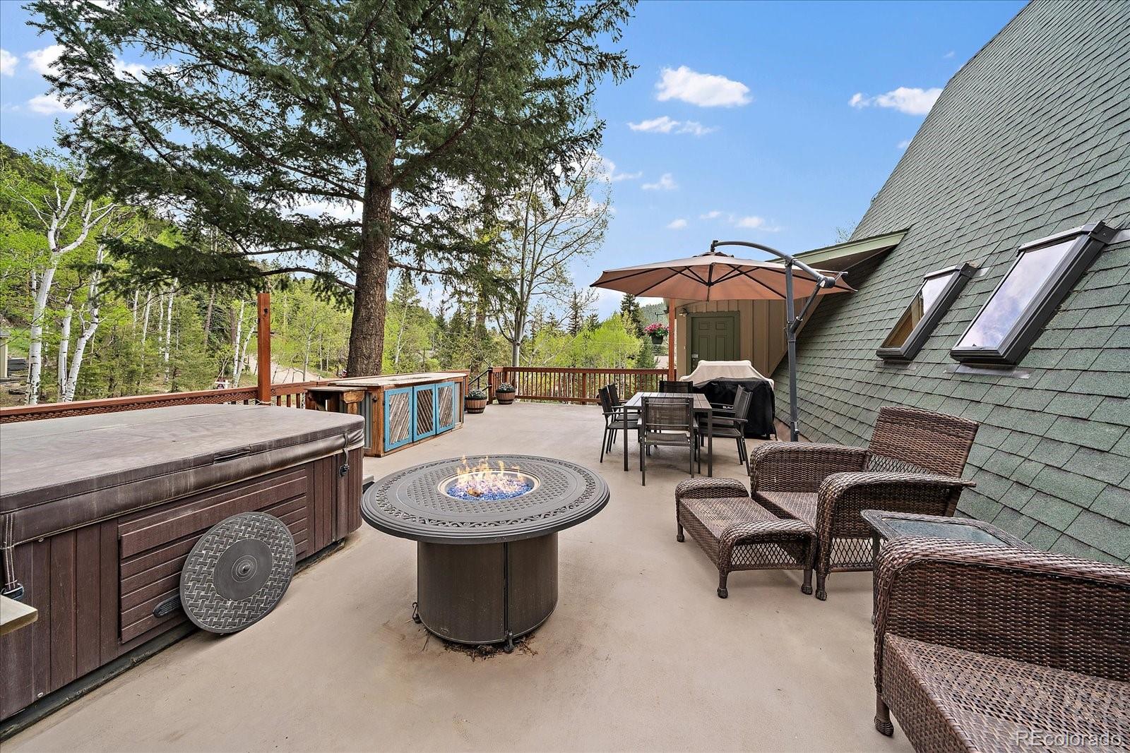 307 Snyder Mountain Road Evergreen, CO 80439 - Photo 5 of 41 a view of a patio with table and chairs potted plants and a barbeque
