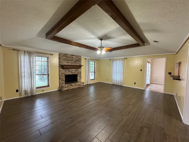 an empty room with wooden floor fireplace and windows
