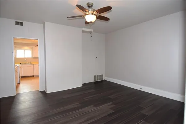 a view of an empty room with window and wooden floor