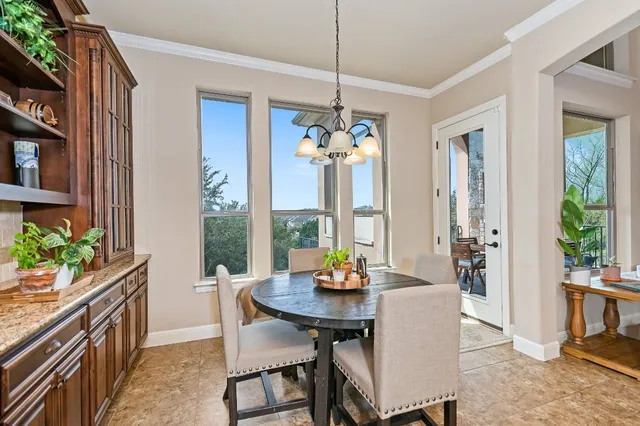 a dining hall with couches a flat tv screen and a dining table with the kitchen view