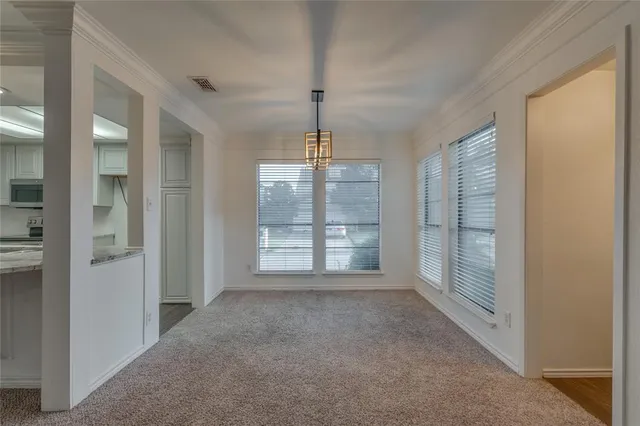 an empty room with chandelier fan and windows