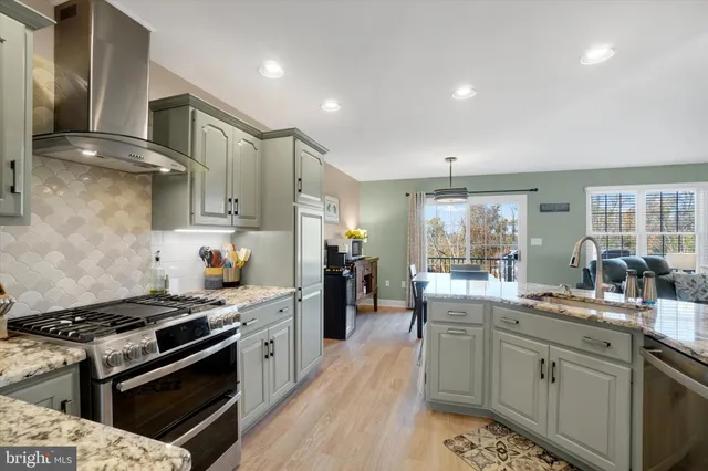 a kitchen with stainless steel appliances kitchen island granite countertop a sink stove and refrigerator