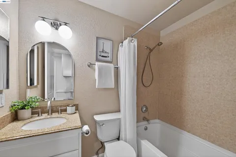 a bathroom with a granite countertop toilet a sink and a bathtub