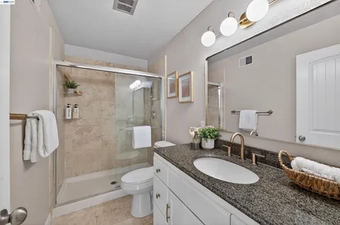 a bathroom with a granite countertop sink mirror toilet and shower