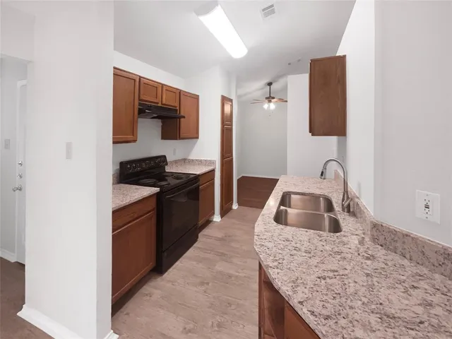a kitchen with granite countertop a sink and a stove with wooden floor