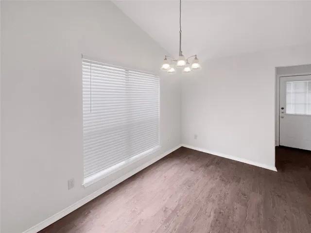 an empty room with chandelier fan and windows