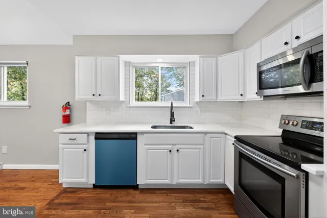 a kitchen with stainless steel appliances white cabinets and a stove top oven