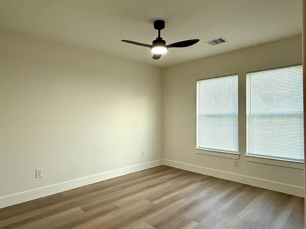 an empty room with wooden floor and windows