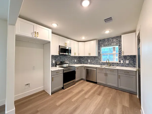 a kitchen with stainless steel appliances granite countertop a stove top oven a sink dishwasher and a refrigerator