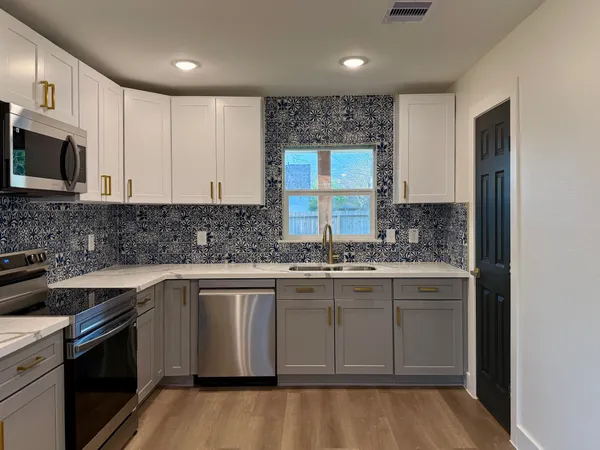 a kitchen with stainless steel appliances granite countertop a sink stove and microwave
