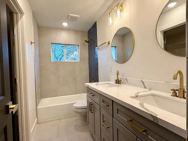 a bathroom with a granite countertop sink mirror toilet and bathtub