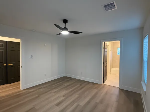 a view of empty room with wooden floor and fan