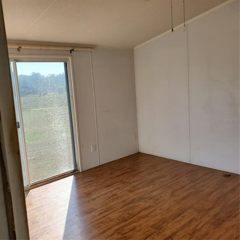 2926 Sharon Road Groveland, FL 34736 - Photo 10 of 16 a view of an empty room with wooden floor and a window