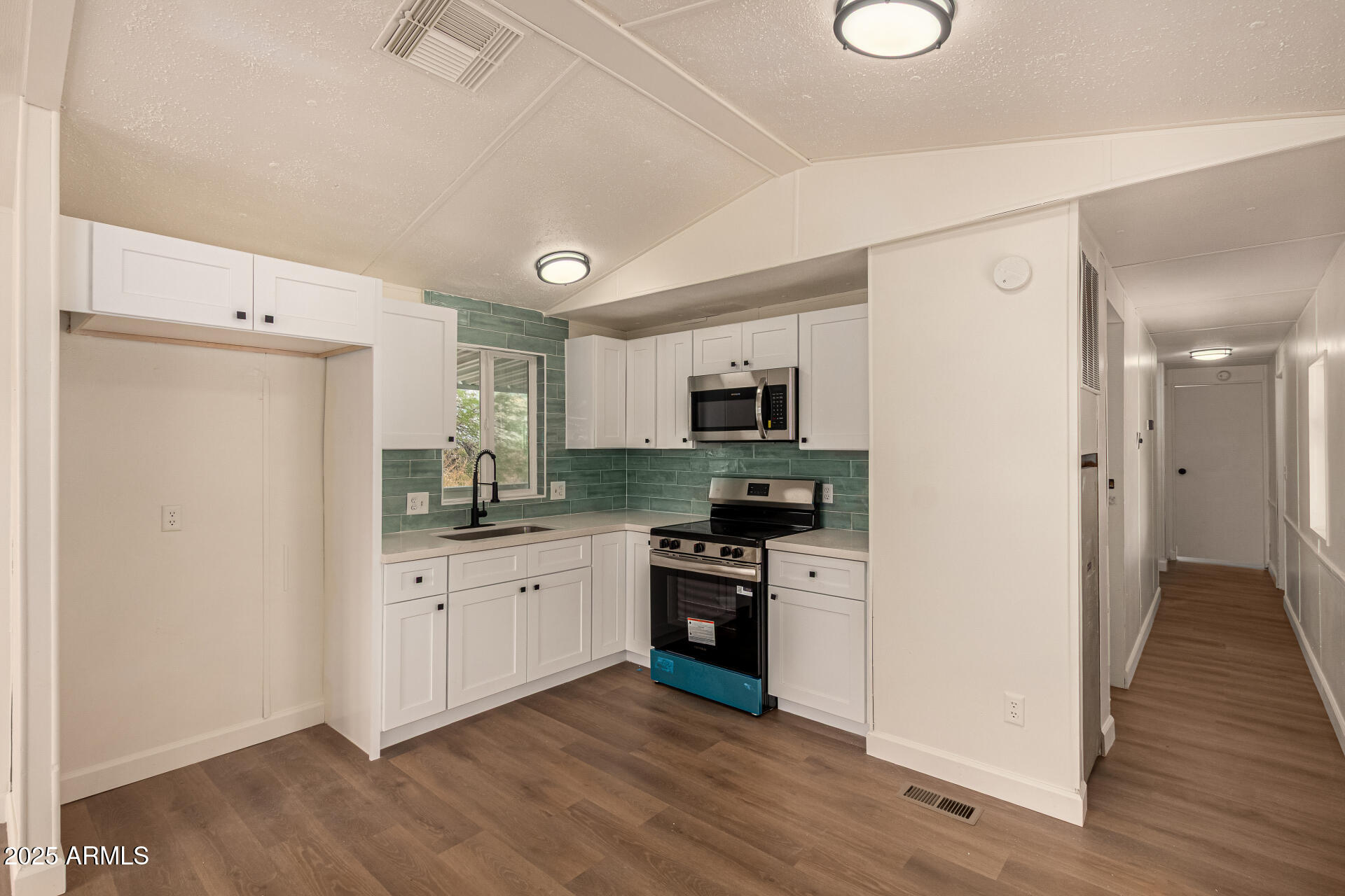 3663 North Thistle Drive Florence, AZ 85132 - Photo 2 of 29 a kitchen with white cabinets and stainless steel appliances
