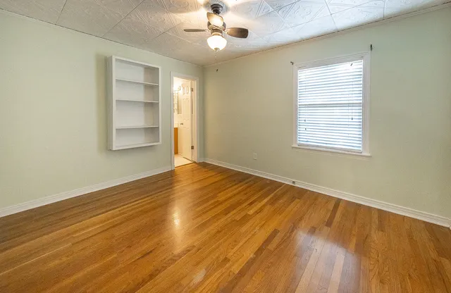 a view of an empty room with wooden floor and a window