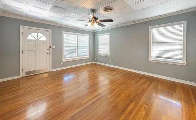 a view of an empty room with wooden floor and a window
