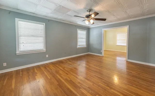 a view of an empty room with wooden floor and a window