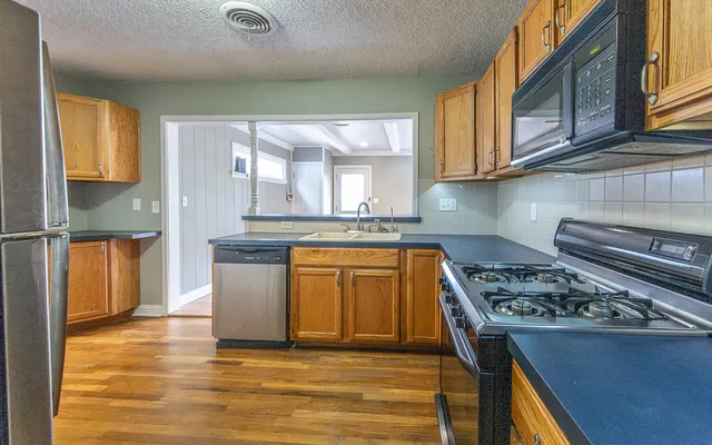 a kitchen with stainless steel appliances granite countertop a stove a sink and a microwave