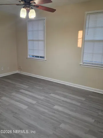 an empty room with wooden floor and windows