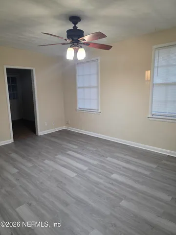 a view of an empty room with wooden floor and a window