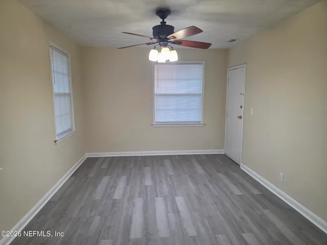 an empty room with wooden floor chandelier fan and windows