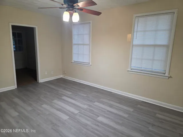 an empty room with wooden floor closet and windows