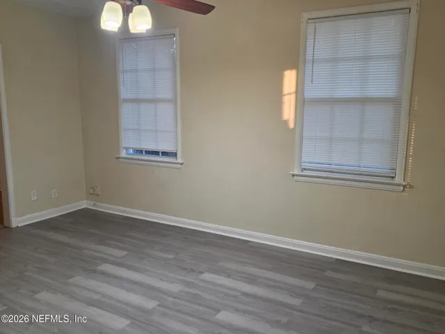 an empty room with wooden floor and windows