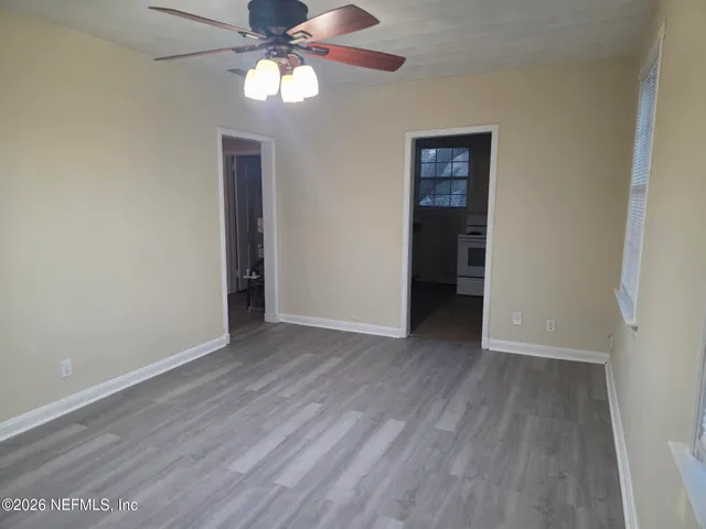 a view of an empty room with window and wooden floor