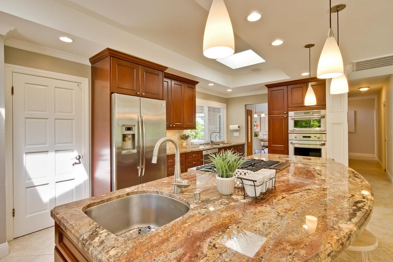 22266 Hartman Drive Cupertino, CA 95014 - Photo 17 of 73 a dinning room with stainless steel appliances kitchen island granite countertop a refrigerator a sink a dining table and chairs with wooden floor
