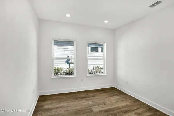 an empty room with wooden floor and windows