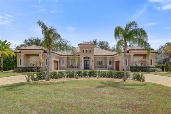 a front view of a house with a garden and trees