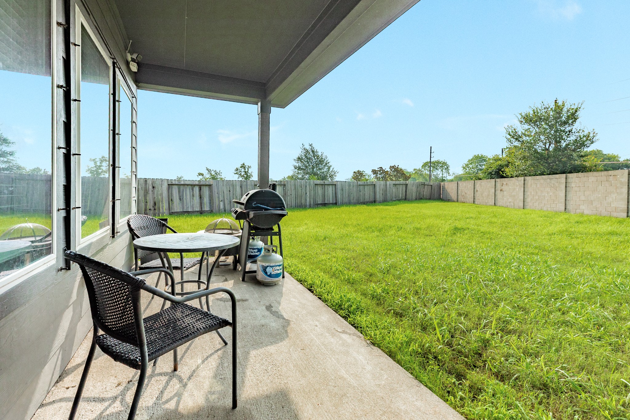 2446 Palisade Crst Drive Rosharon, TX 77583 - Photo 27 of 30 This photo shows a spacious backyard with a covered patio area. There's a small table with chairs and a grill, perfect for outdoor dining and relaxation. The yard is enclosed by a wooden fence, providing privacy and security.
