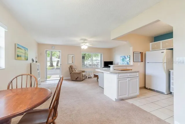 a large white kitchen with a refrigerator a stove a dining table and chairs