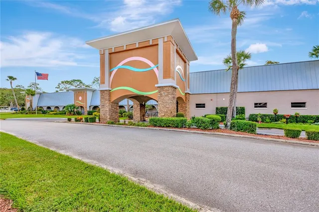 a sign board with flower plants and brick building in front of it