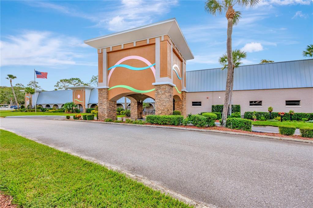 11723 Boynton Lane, Unit 1 New Port Richey, FL 34654 - Photo 23 of 31 a sign board with flower plants and brick building in front of it