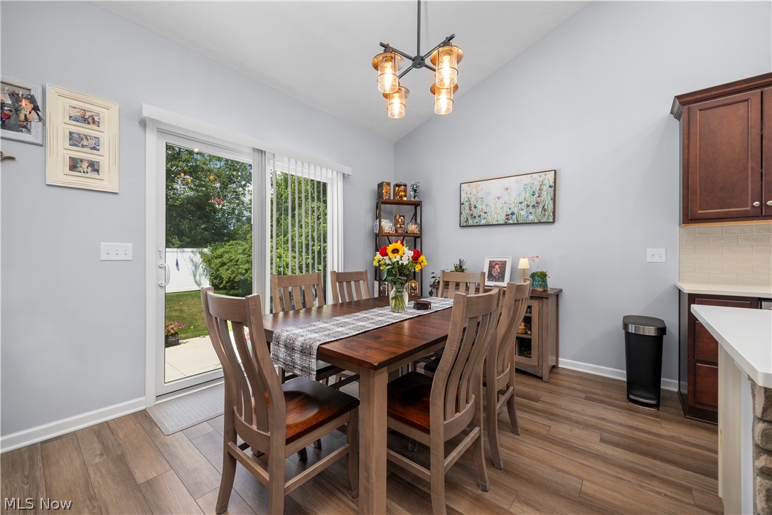109 West Spring Drive Elyria, OH 44035 - Photo 19 of 46 Dining area featuring vaulted ceilings, wood-finish flooring, a contemporary chandelier, and direct access to an outdoor patio via sliding glass doors