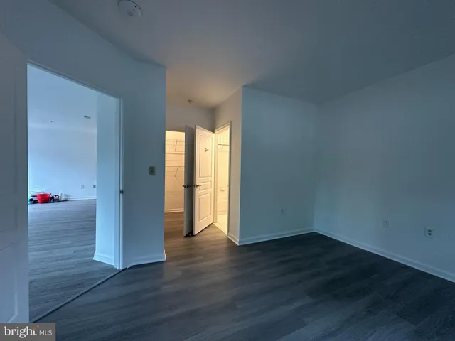 a view of an empty room with wooden floor and closet